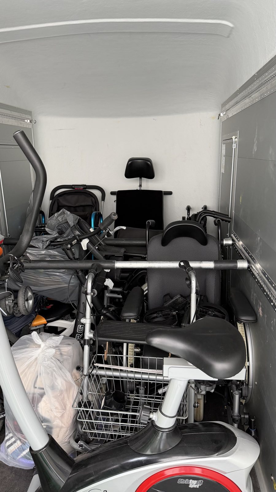 De volgeladen aanhanger met rolstoelen en looprekken