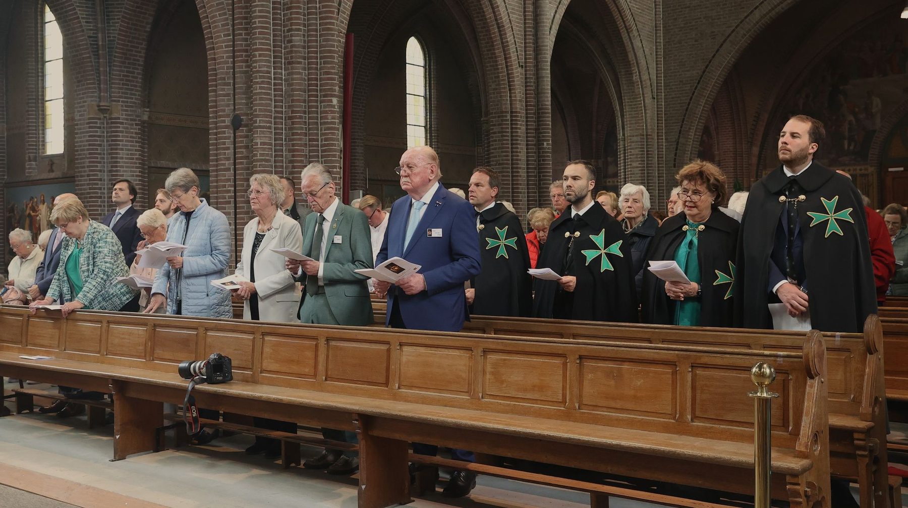 Confrères en consoeur in de kerkbanken