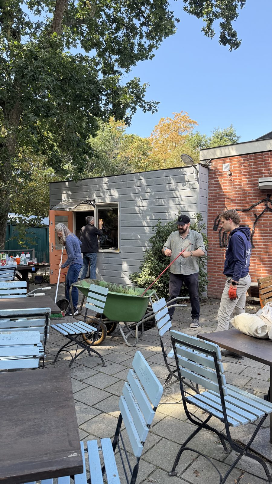 Deelnemers vegen het terras en maken de kiosk schoon