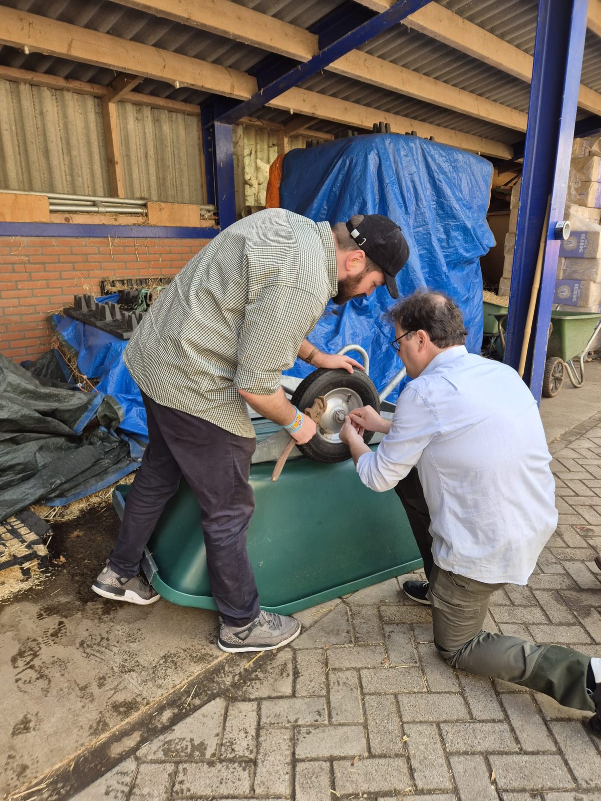 Twee deelnemers zetten het wiel terug in een kruiwagen